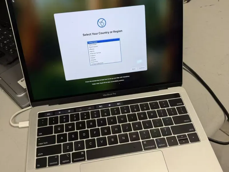 A MacBook Pro unit booting up on a workbench in the grading warehouse
